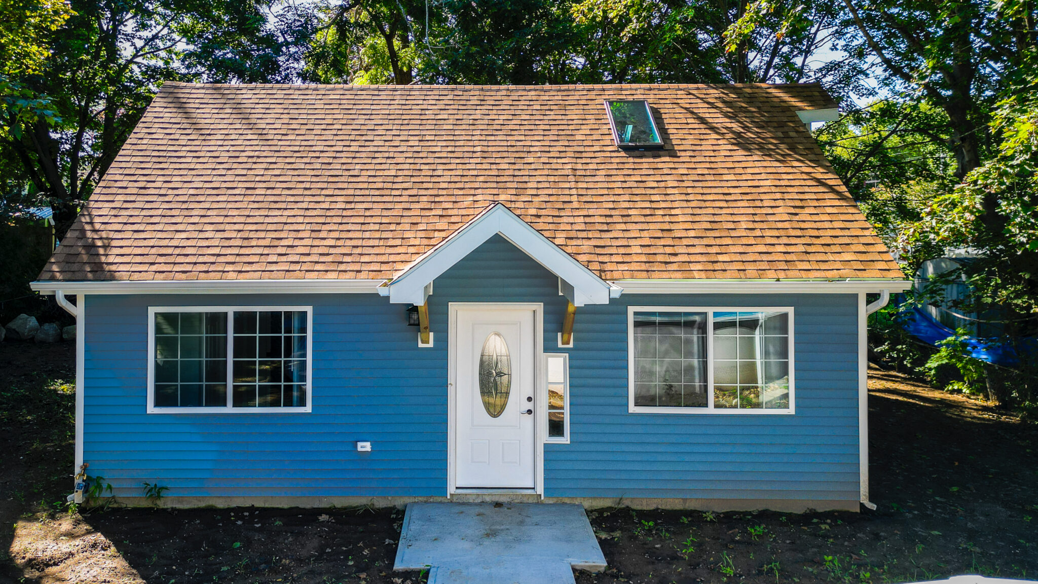 Front exterior of completed blue house with white trim, entrance and shingled roof in Groton, CT