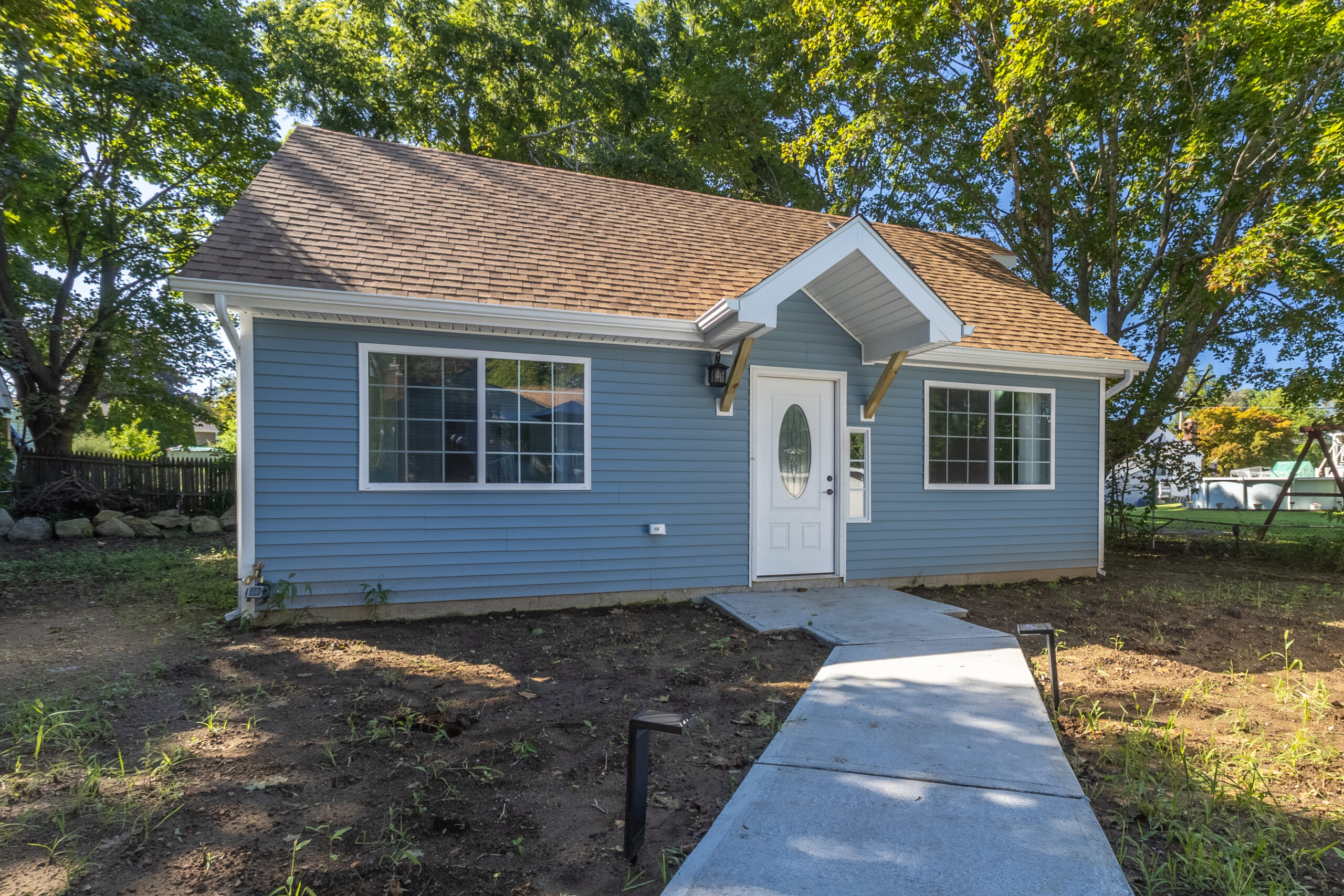 Completed blue house construction with white trim and concrete walkway