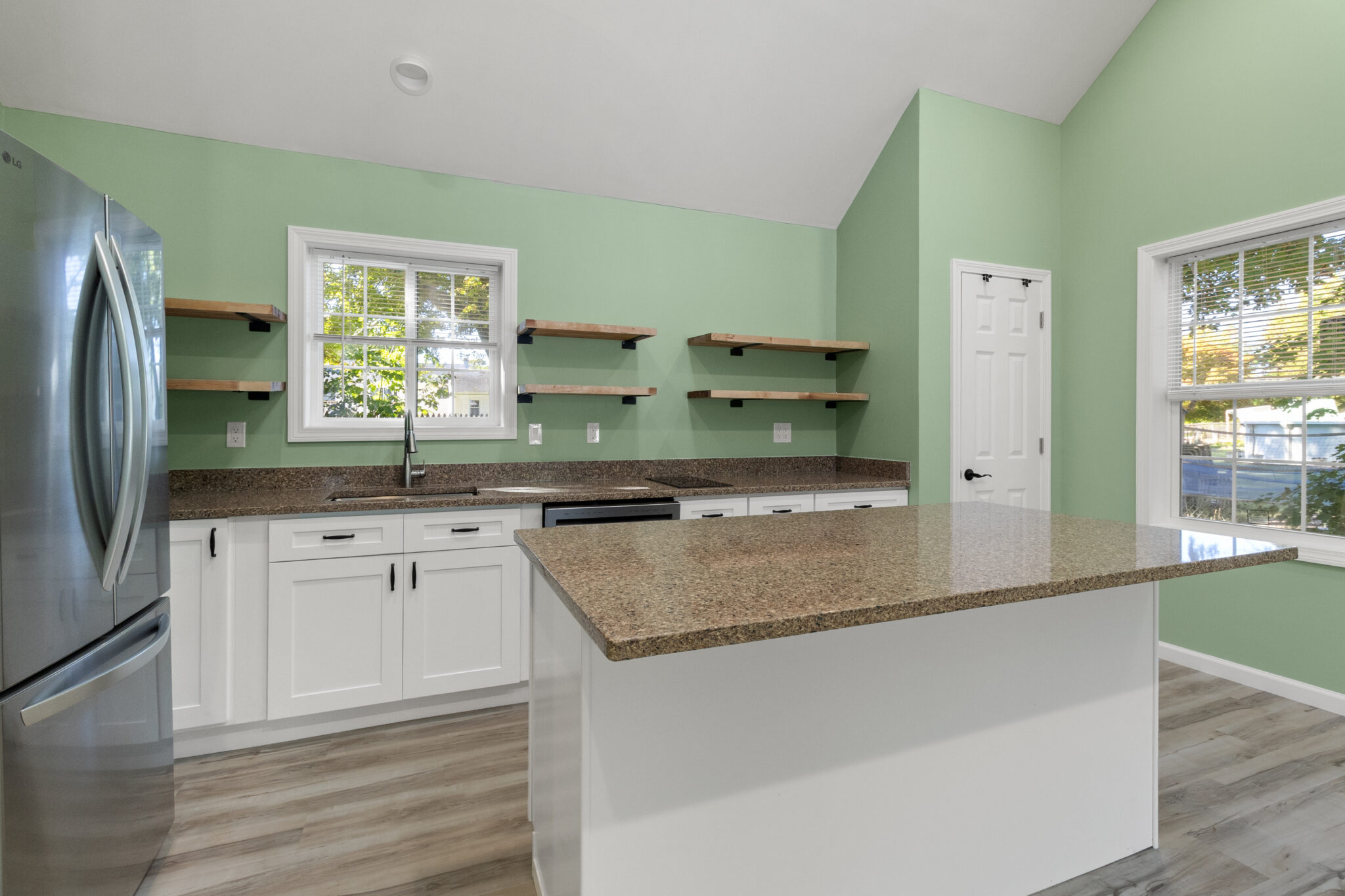 Completed kitchen with white cabinets, stone countertops, open shelving and green walls in Groton, CT