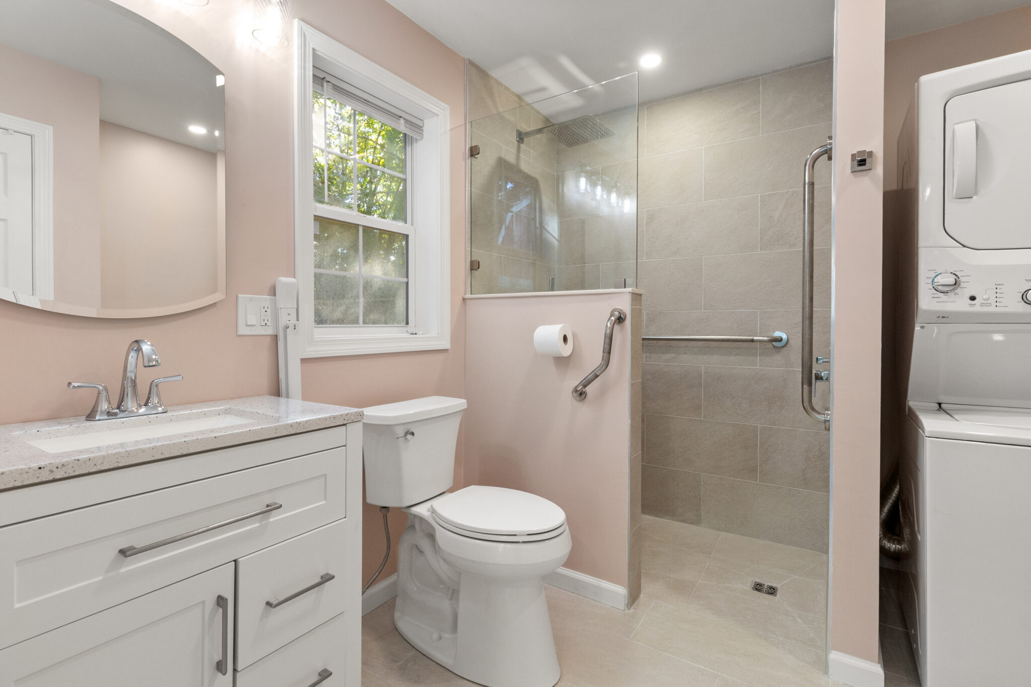 Completed bathroom with white vanity, glass-enclosed shower and window in Groton, CT