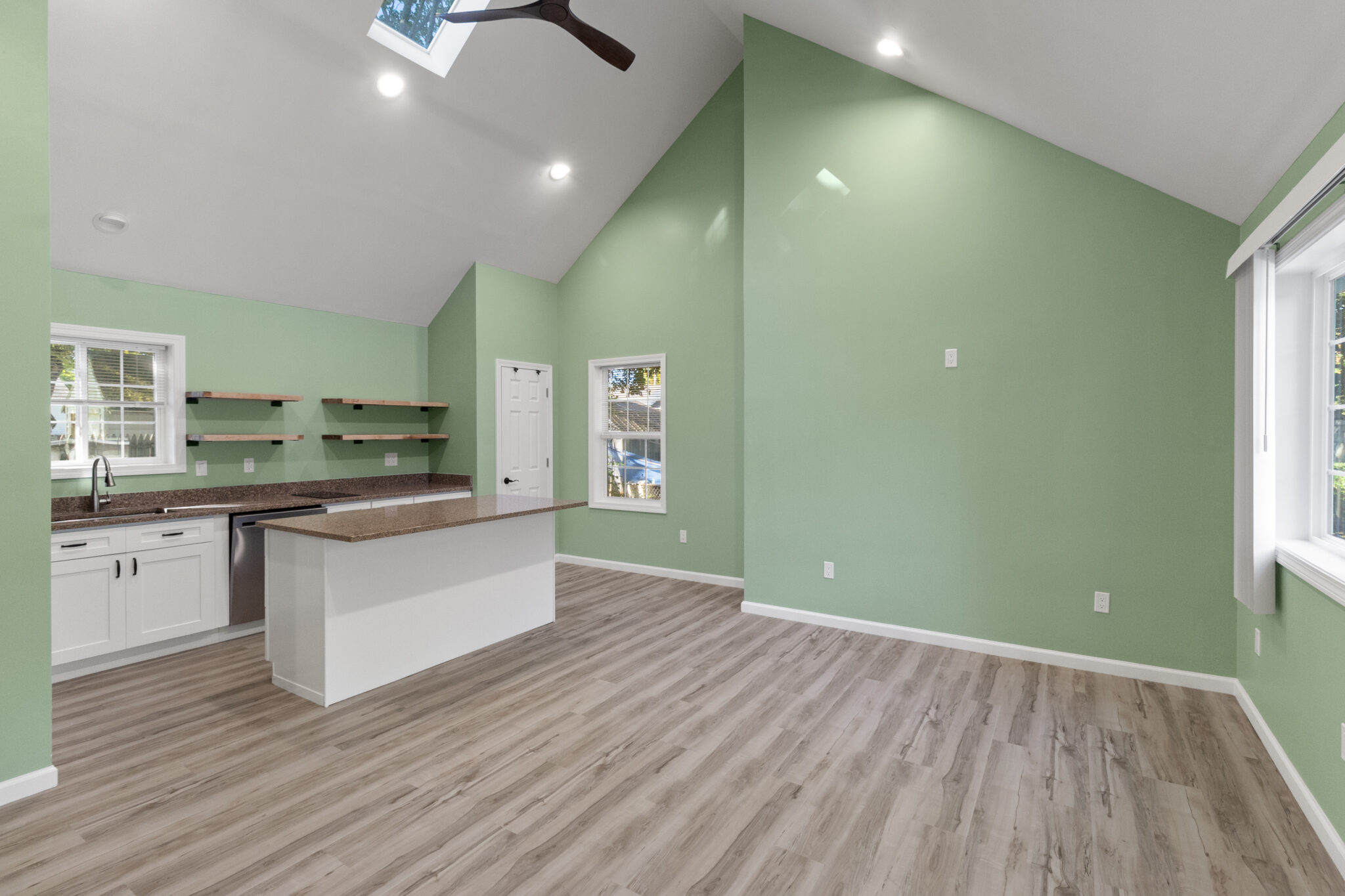 Completed open-plan home interior with green walls, vaulted ceiling and kitchen in Groton, CT