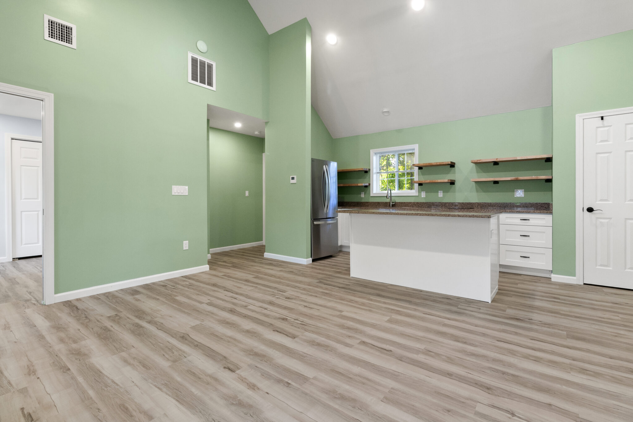 Finished living area with vaulted ceiling, green walls and open kitchen in Groton, CT