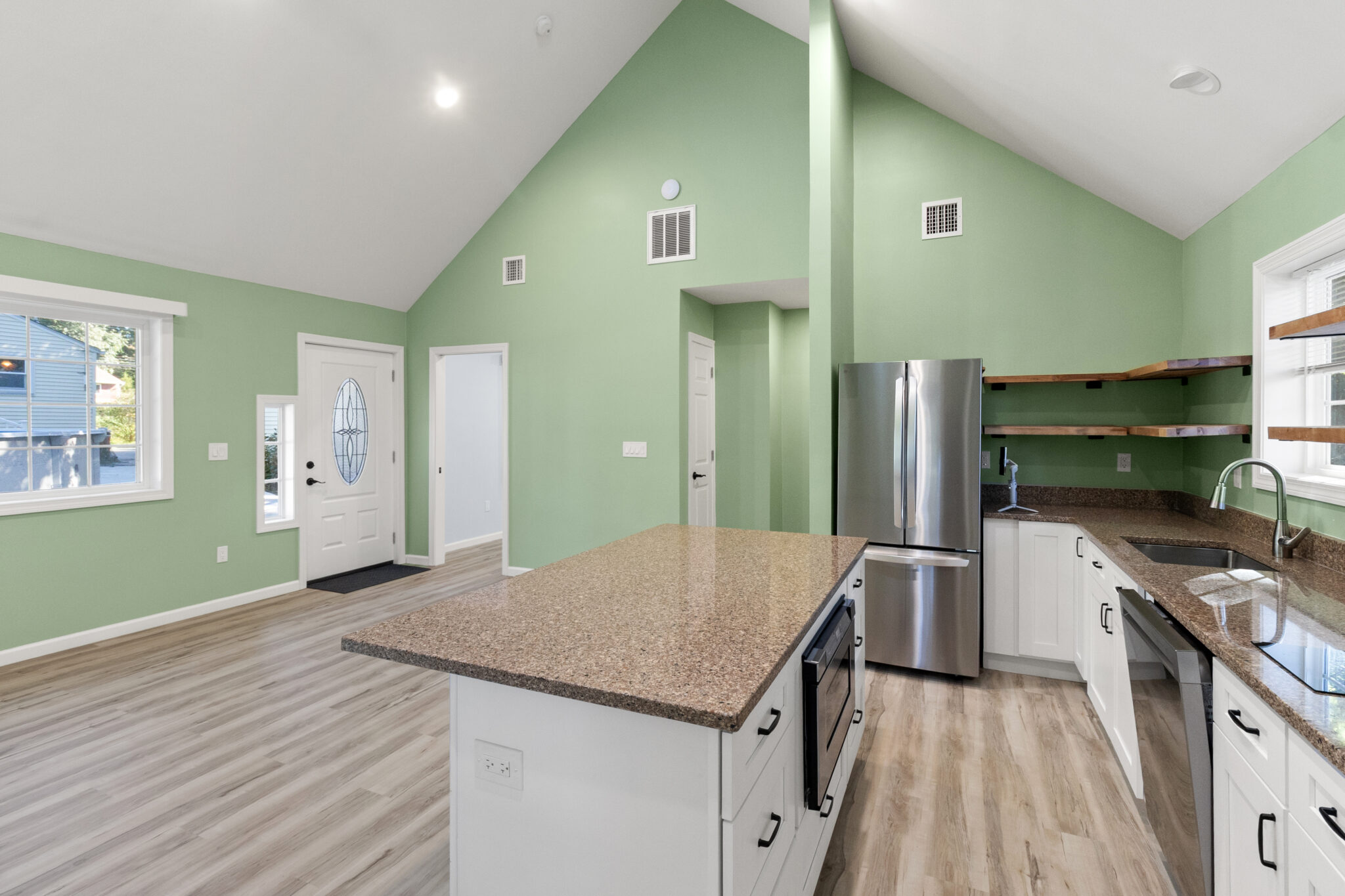 Completed kitchen with center island, white cabinets, stainless steel appliances and green walls