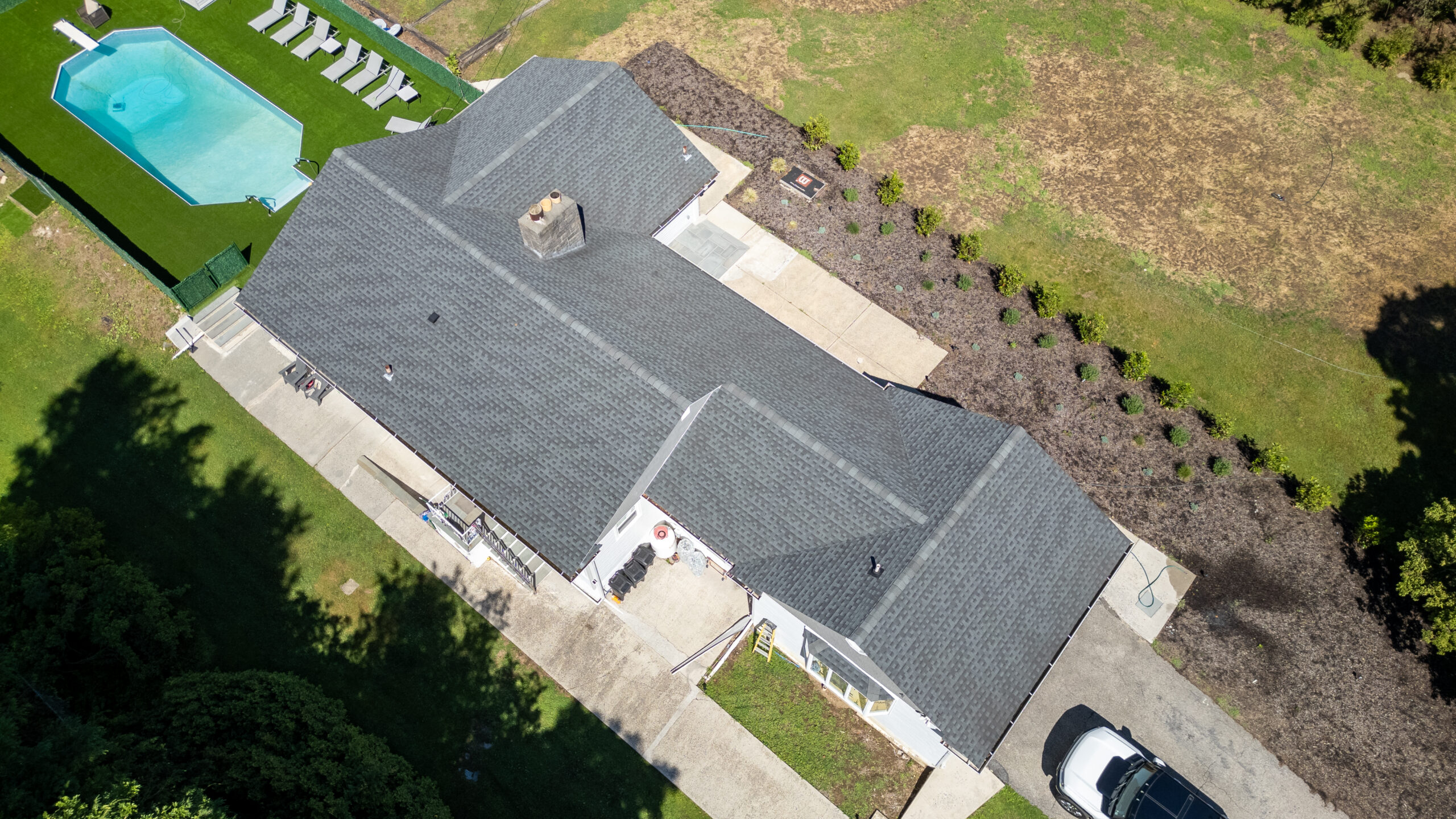 Aerial drone view of residential roof, driveway and surrounding property